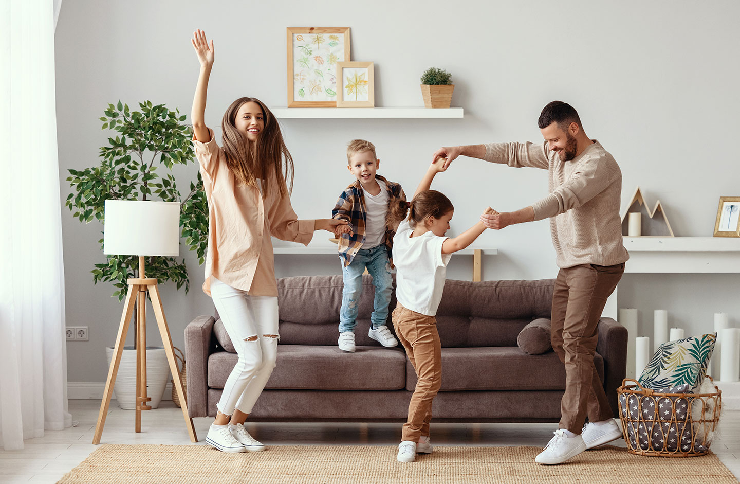 Familie tanzt fröhlich im Wohnzimmer.