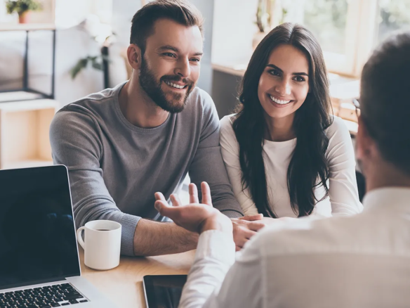 Junges Paar bei der Immobilienberatung mit einem Experten am Tisch