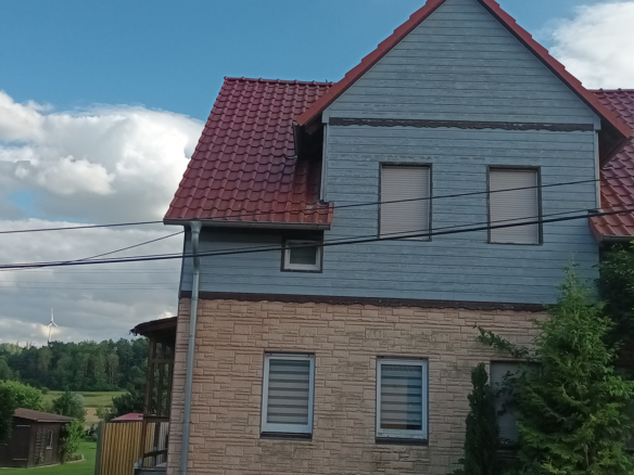 Vorderseite eines sanierungsbedürftigen Hauses mit Holzfassade und modernem Dach in ruhiger Lage von Ellrich-Gudersleben