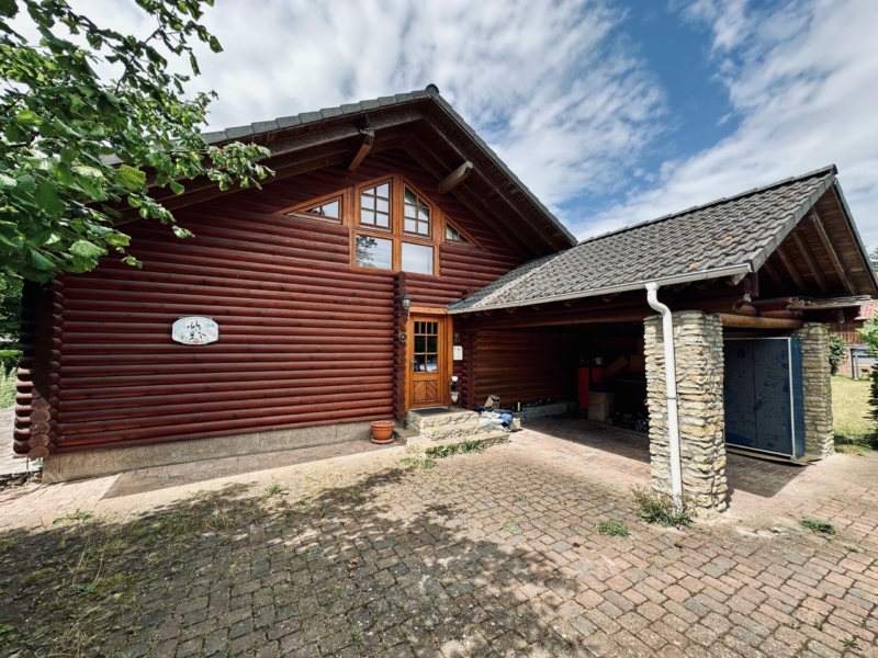 Eingangsbereich zum Blockhaus mit Holzfassade und Carport