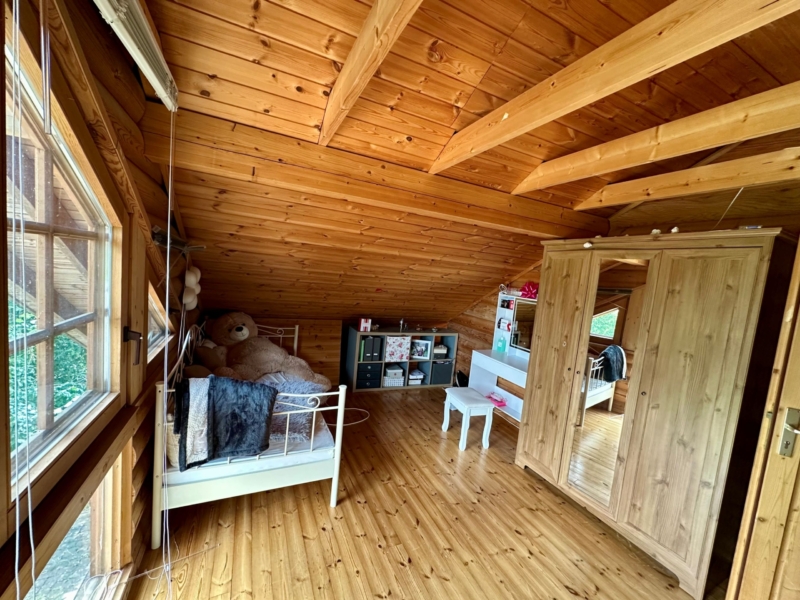 Lichtdurchflutetes Kinderzimmer mit offenen Holzbalken im Spitzboden