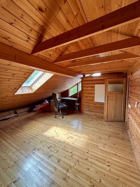 Raum mit Bürotisch und Stuhl im Spitzboden mit offenen Balken