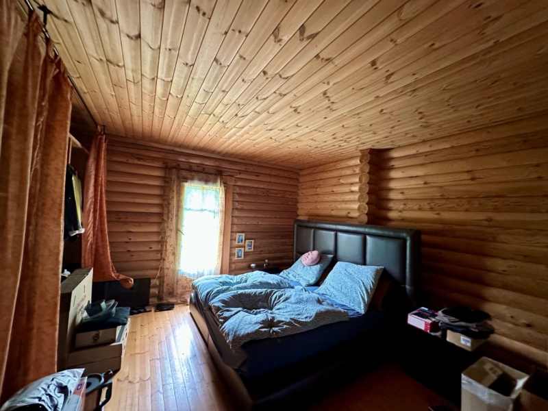 Schlafzimmer mit großem schwarzen Bett im Holzhaus
