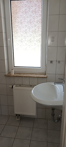 Gefliestes Gäste-WC mit Fenster, Heizkörper und Waschbecken im Einfamilienhaus in Nordhausen